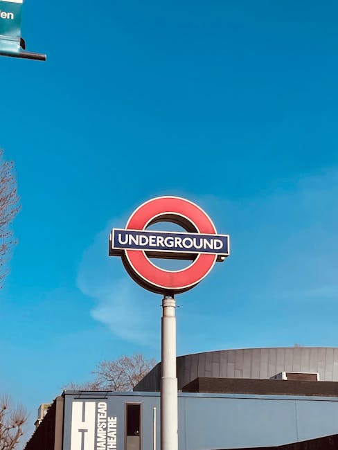 Exterior view of a street in West Hampstead with a black coffee shop on the corner, displaying a large window and a sign reading 'COFFEE'. In front of the shop, a person dressed in brown is entering t